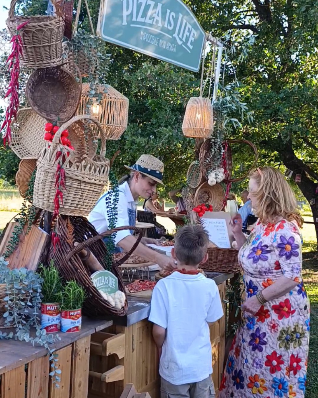 Servizio Pizza is Life al banco in legno, tra cesti intrecciati, luci e ospiti in giardino